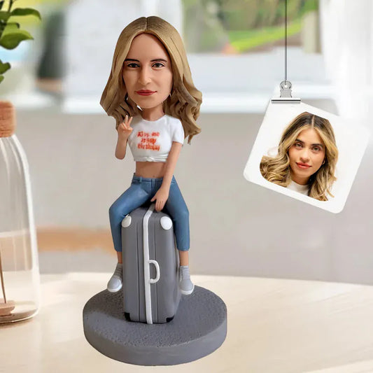 Custom female bobblehead sitting on a suitcase handcrafted from photos.webp