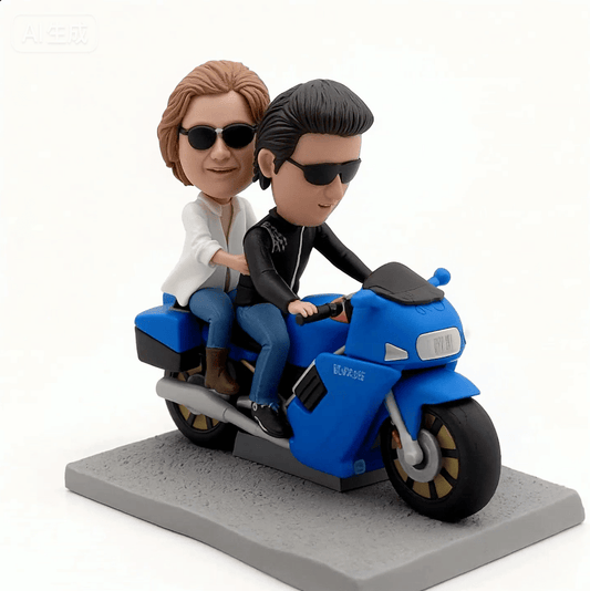 Bobblehead figures of two people riding a blue motorcycle on a white background