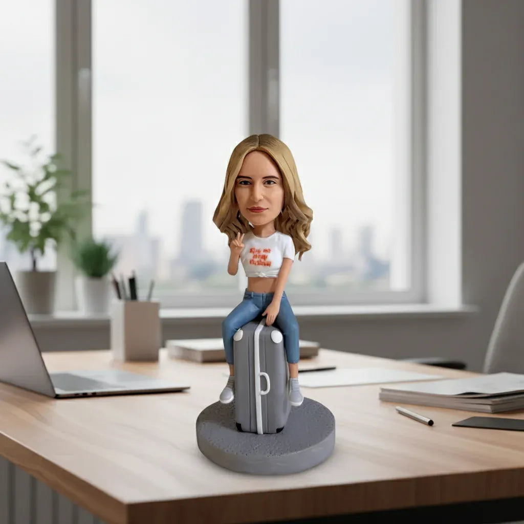 Custom female bobblehead sitting on a suitcase handcrafted from photos.webp