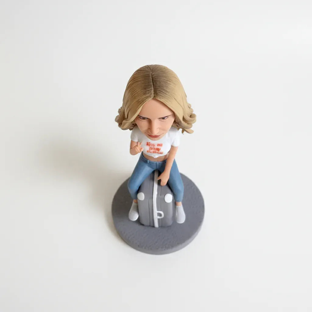 Custom female bobblehead sitting on a suitcase handcrafted from photos.webp