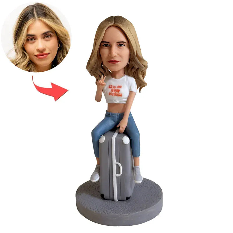 Custom female bobblehead sitting on a suitcase handcrafted from photos.webp